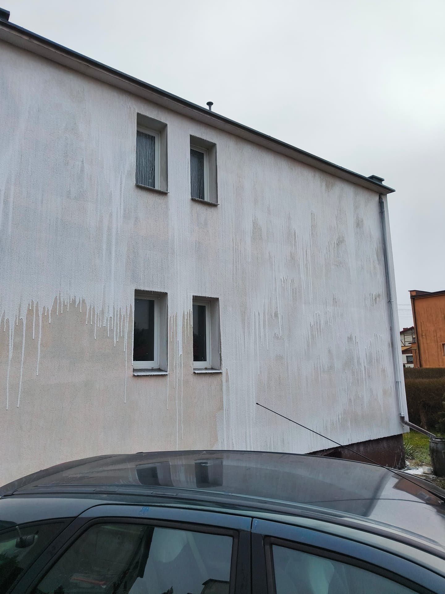 Elewacja domu w trakcie mycia — usuwanie zacieków i zazielenień